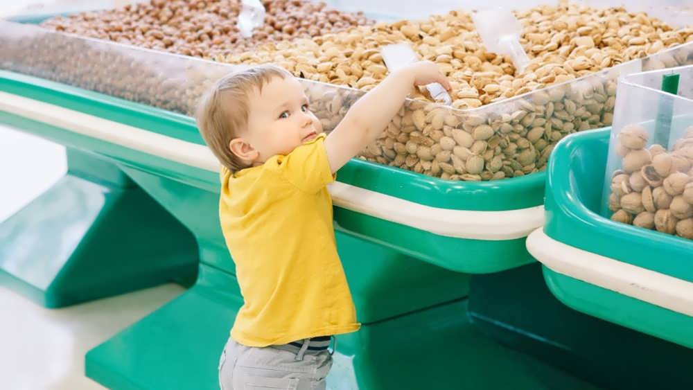 کودک ناز در انتخاب آجیل در یک خواربارفروشی
